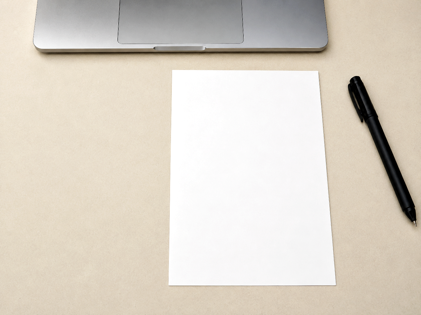 A4 sheet folded in half on a beige desk with a black pen on the right.