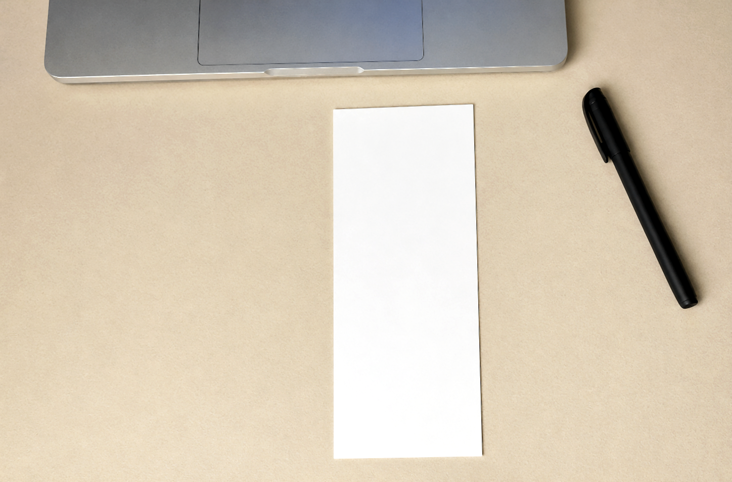 Narrow folded paper strip on a beige desk with pen and laptop.