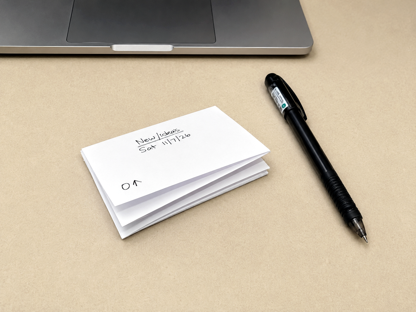Completed PocketMod booklet beside a black pen with handwritten notes.